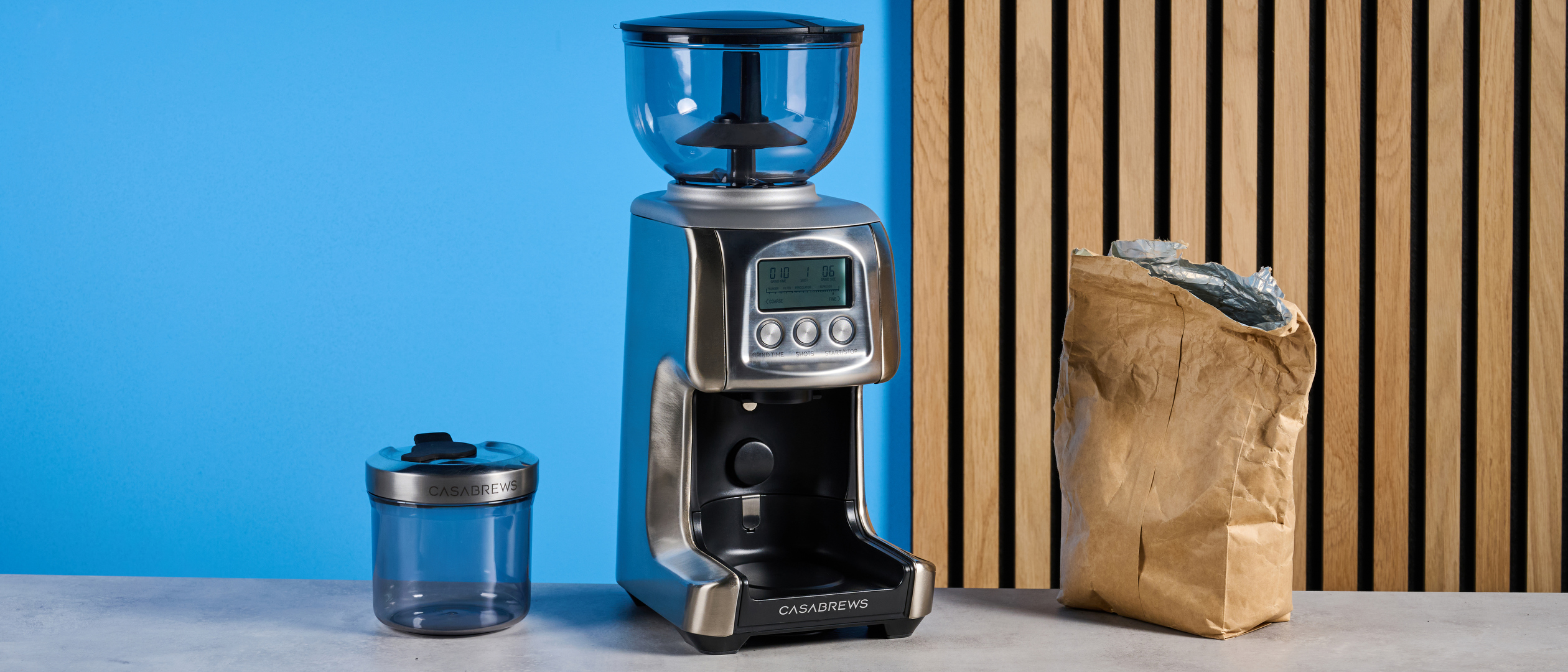 the casabrews tornado coffee grinder in silver showing the LED screen, grind adjustment dial, and photographed against a blue background