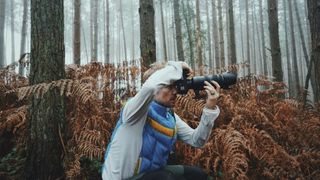 Photographer taking pictures with a camera in a misty woodland