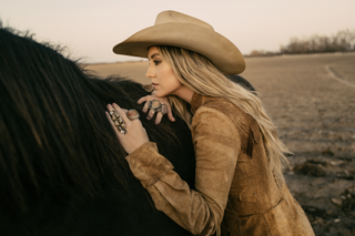 lainey wilson poses with a horse in a whirlwind promo shot