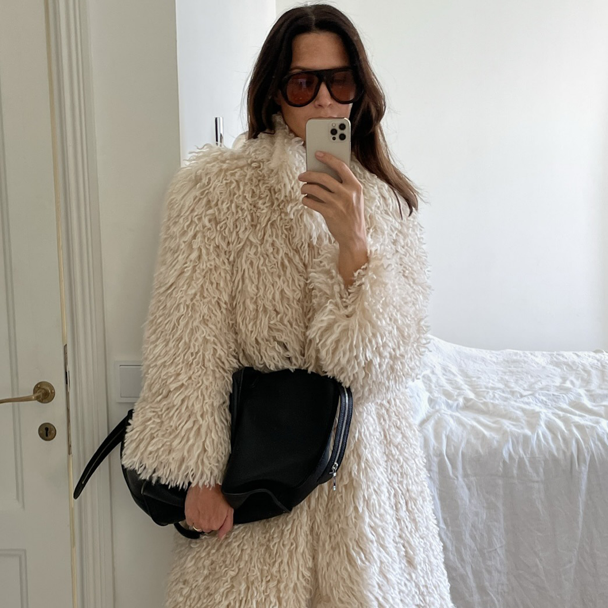 Woman wearing furry jacket and white denim jeans.