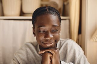 boy smiling with hands clasped and eyes closed