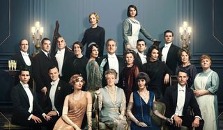 Downton Abbey cast lineup in front of an ornate blue wall