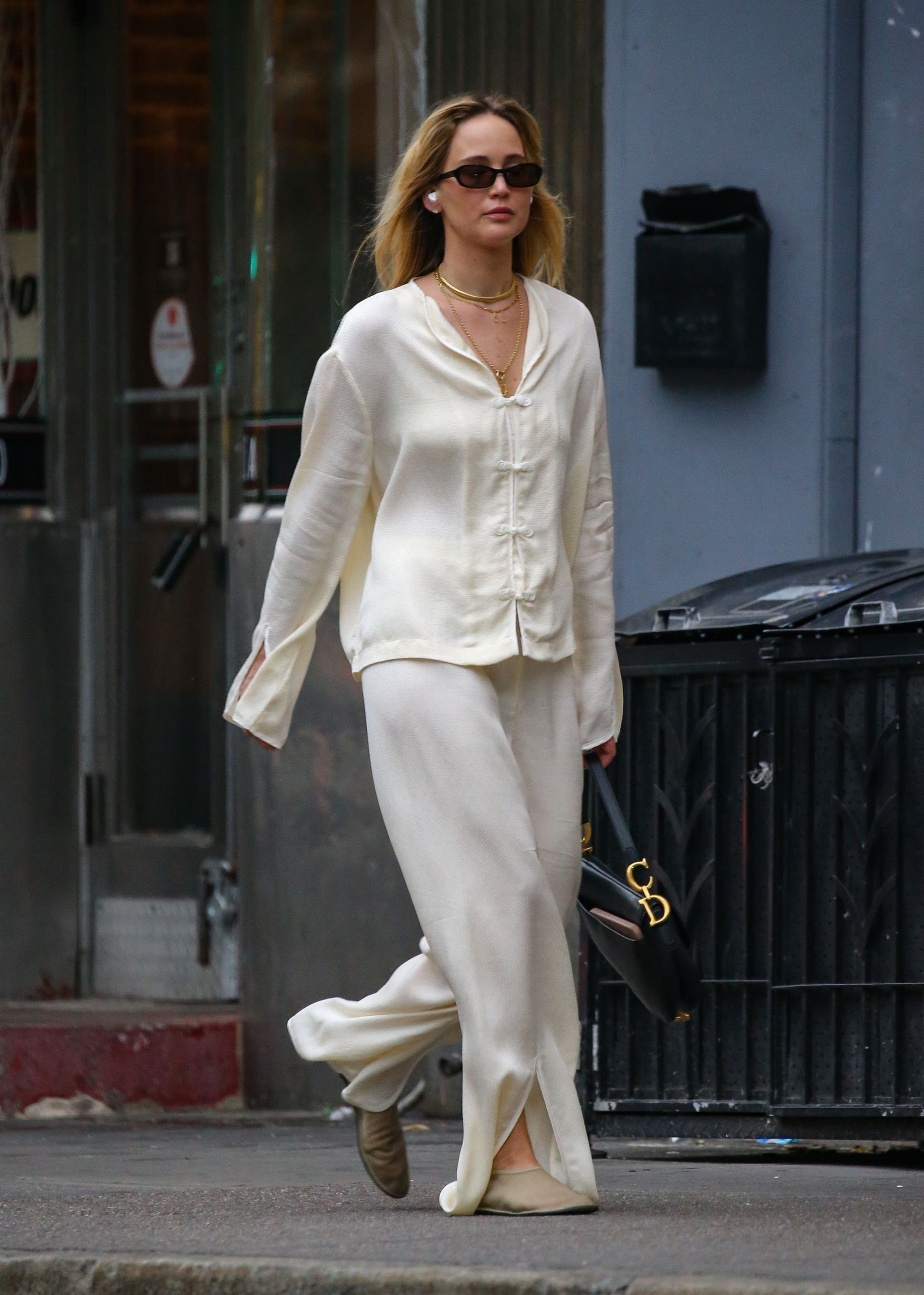 Jennifer Lawrence walks down the streets of New York wearing a cream satin two-piece with mesh ballet flats and a Dior Saddle bag.