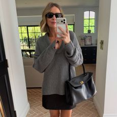 Woman wears Reformation grey scoop neck cashmere jumper and black mini skirt