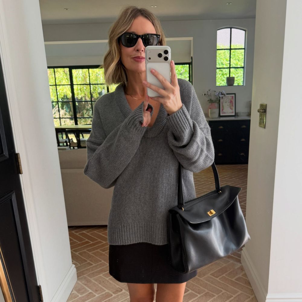 Woman wears Reformation grey scoop neck cashmere jumper and black mini skirt