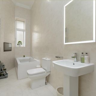 bathroom with cream tile wall white bathtub commode and wash basin
