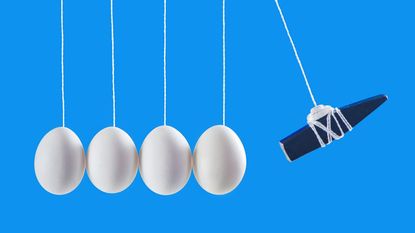 Several eggs suspended on ropes in a straight line with a weight poised to smash into them.