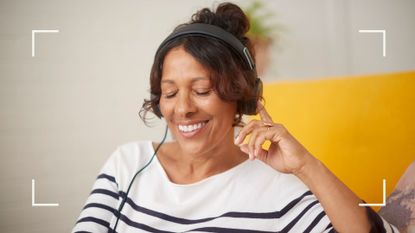 Woman smiling listening to the best podcasts for self-improvement 2023 with headphones, sitting next to yellow sofa and wearing striped tshirt