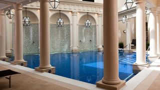 A swimming pool flanked by classical columns and lanterns