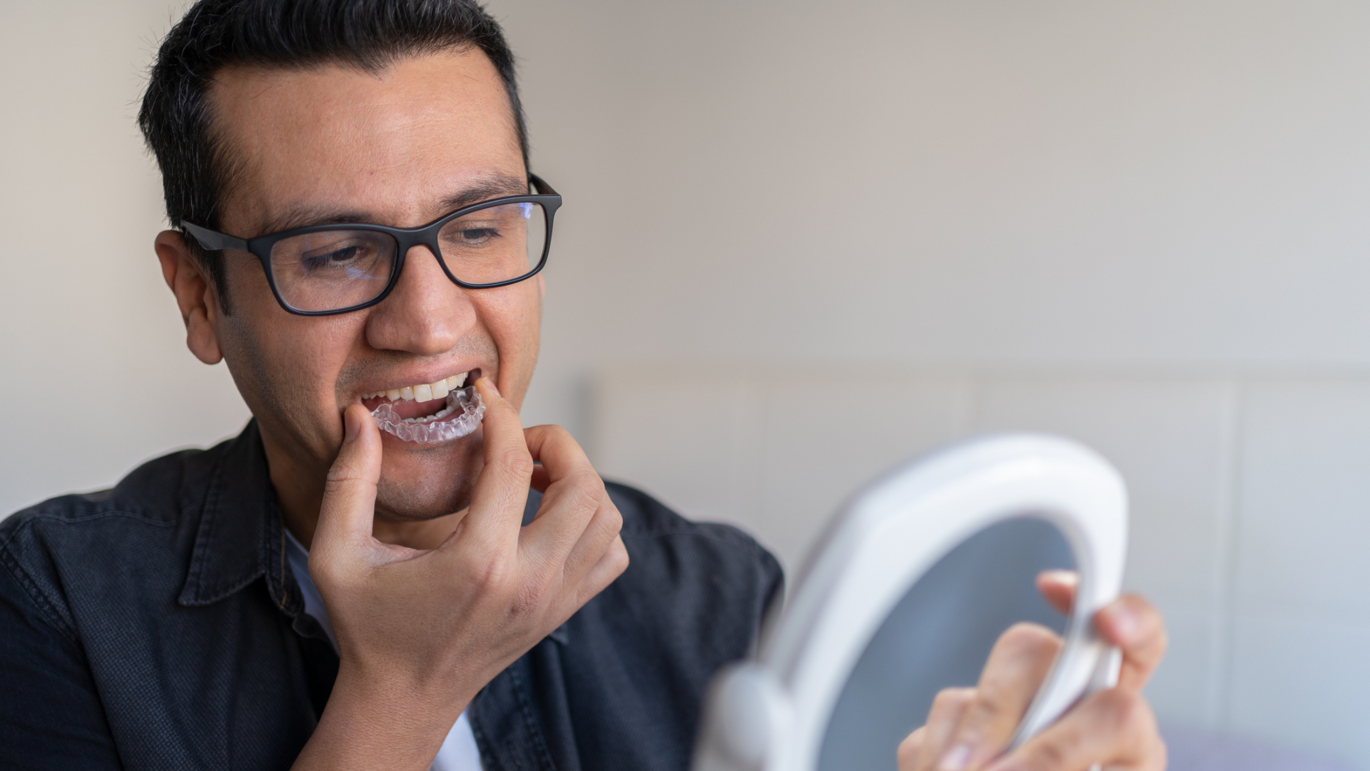 A man putting a sleep apnea mouthguard in while looking at a mirror