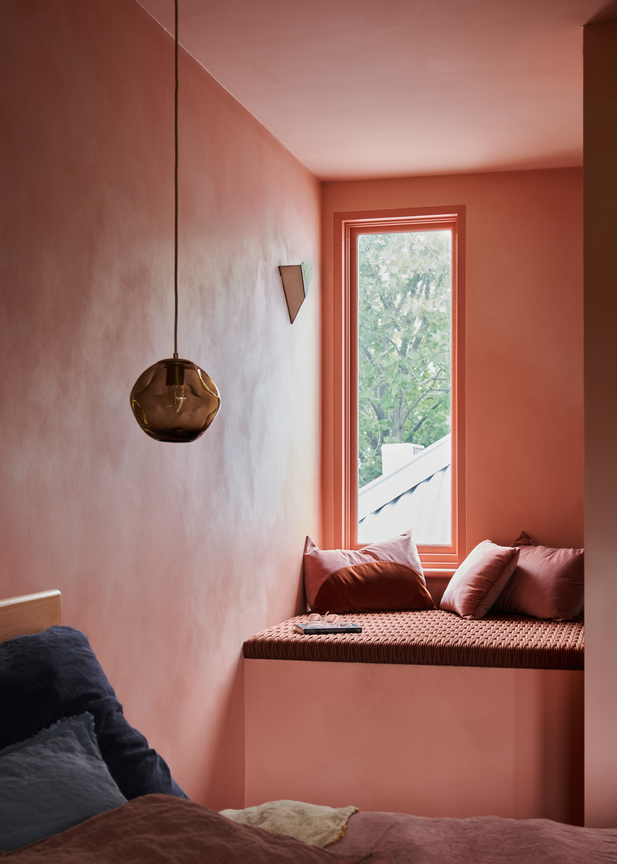 A blush room with a cozy corner by a window by a hanging pendant lamp
