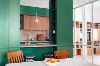 green kitchen seprated from living room by white partition wall