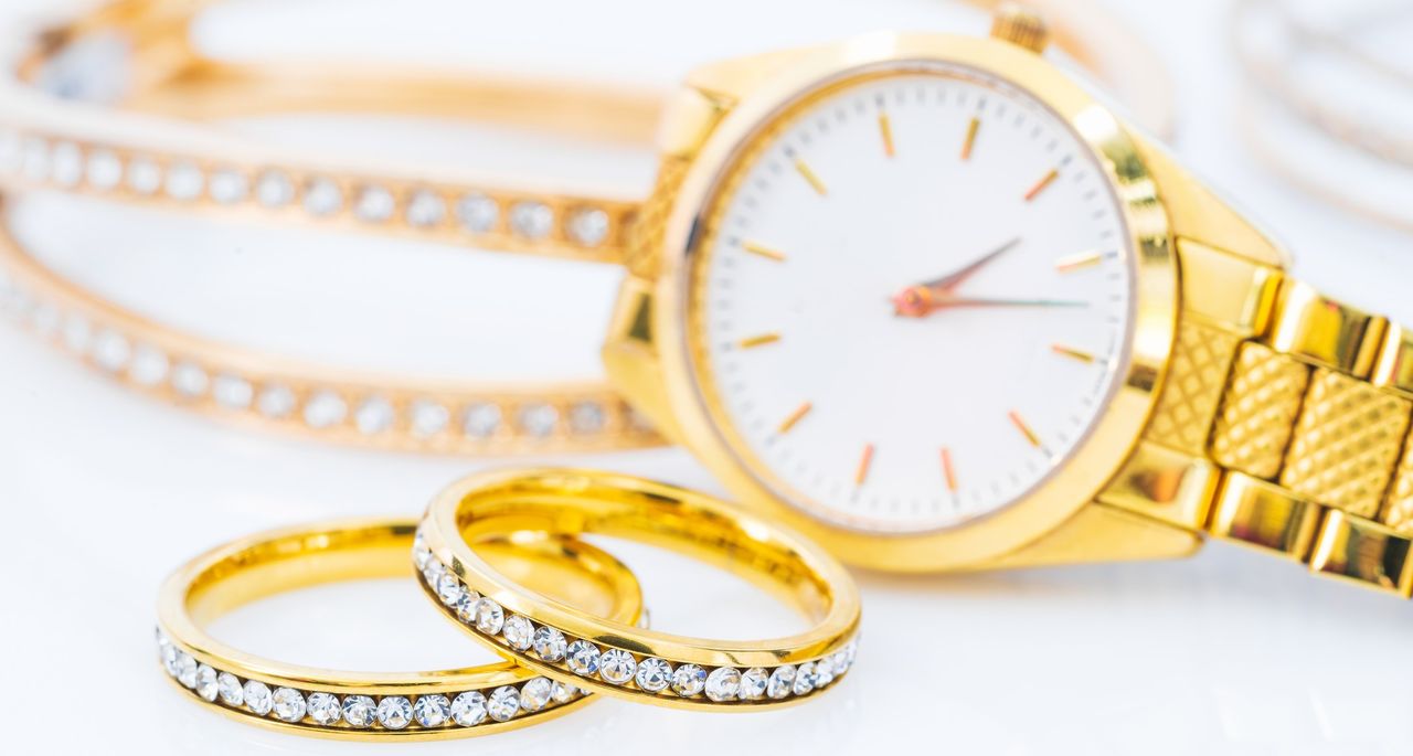 Close-Up of gold watch, diamond rings and bracelet on a table