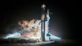 A towering Starship Flight 3 rocket and Super Heavy booster atop the launch pad at night in a fueling test