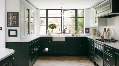U-shaped kitchen with forest green cabinets, ceramic farmhouse sink and crittall windows