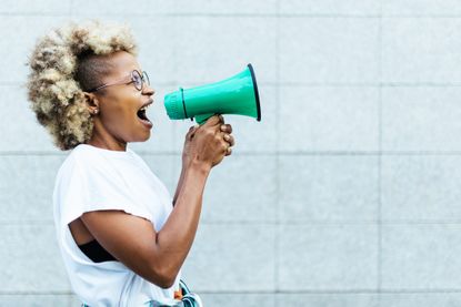 Young adult woman shouting through a megaphone outdoors