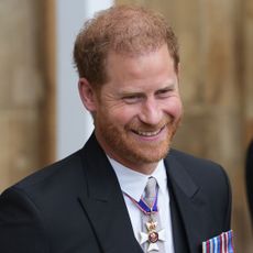 Prince Harry smiles in a black suit.