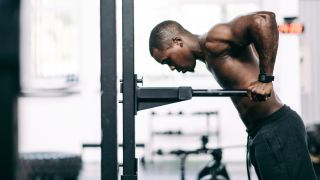 Man performs triceps dips using dip bars in gym