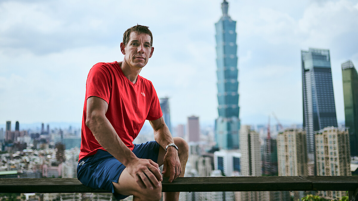 Alex Honnold sat in front of the Taipei 101 skyscraper