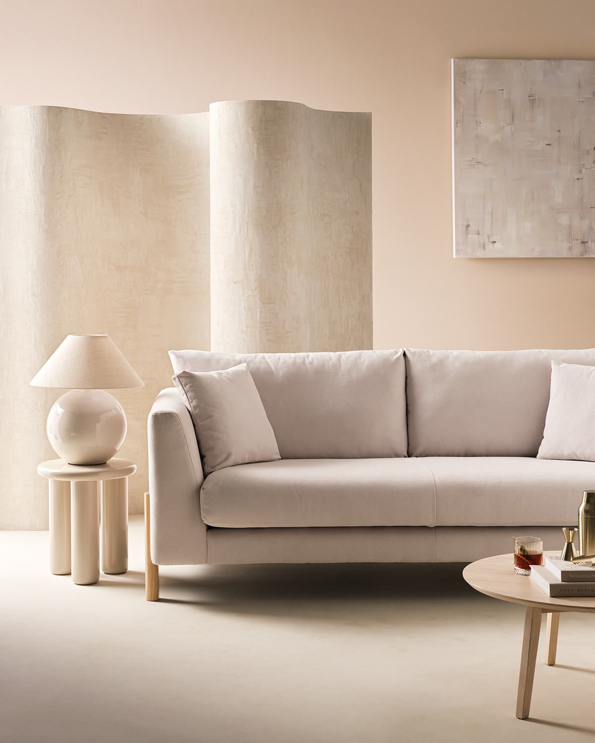 Image of a room drenched in an off-white color. There is an off-white room divider and a light gray/off-white sofa. Beside the sofa is a high-gloss side table with a matching sphere table lamp.