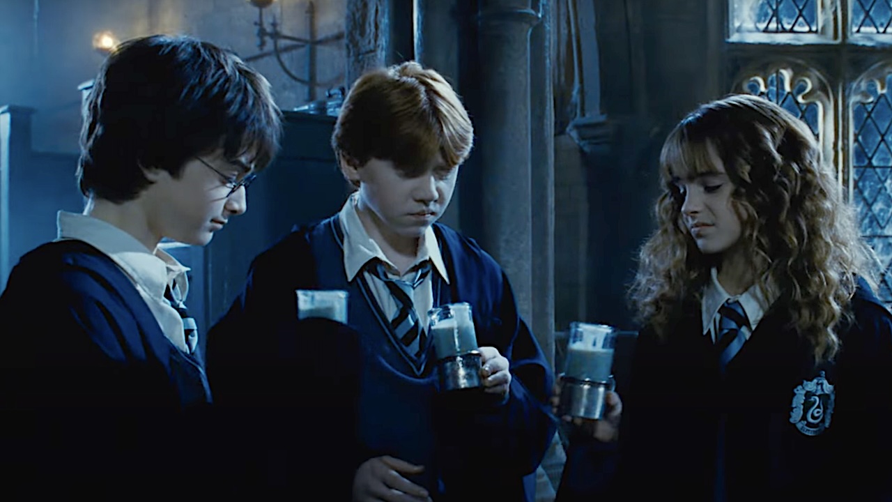 Harry Potter, Ron Weasley, and Hermione Granger holding muddy looking glasses of Polyjuice Potion while wearing Slytherin robes in 2002&#039;s Harry Potter and the Chamber of Secrets. 