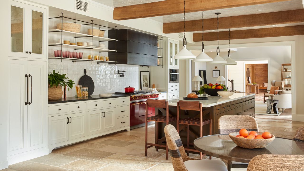 kitchen with red range cooker white cabinets and open shelves large island with bar stools and round breakfast table