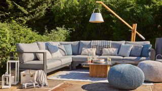 outdoor living room idea with L-shaped sofa and floor lamp lighting