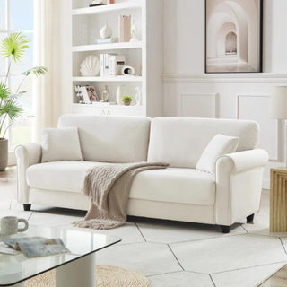 A white sofa with a throw blanket draped on top.