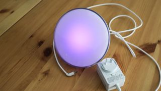 Philips Hue Go 2 in purple light with charger on a table