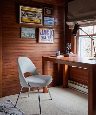 office with dark wood cladding, wooden table and retro style white chair