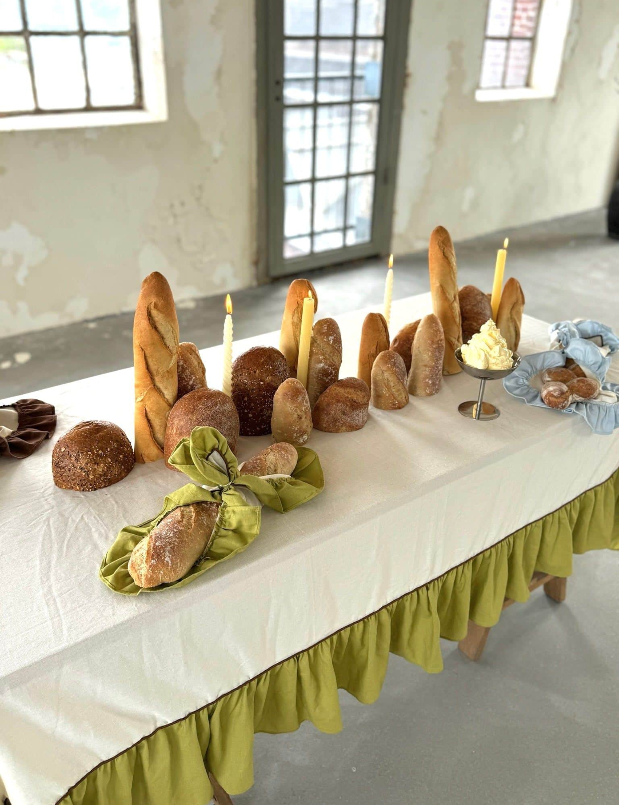 Surrealist tablescape featuring ruffle border table linens and sliced baguettes
