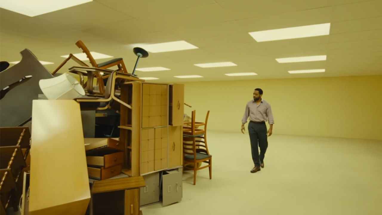 Chiwetel Ejiofor walking next to a pile of old furniture in the backrooms.