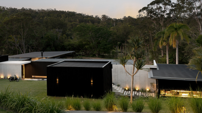modern one story home set amongst the tree with lots of outdoor lighting 