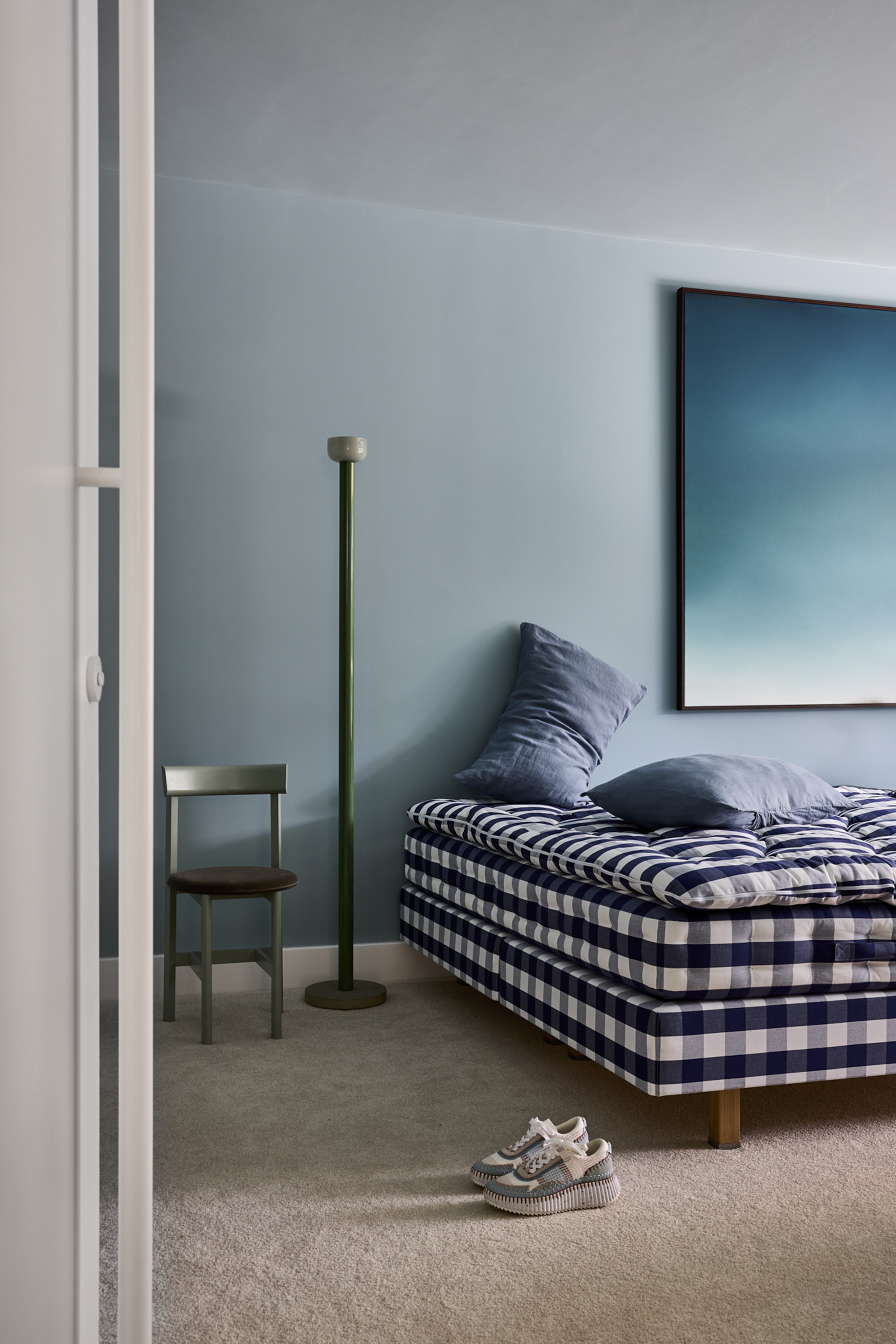 hastens bed in a light blue room with green floor lamp