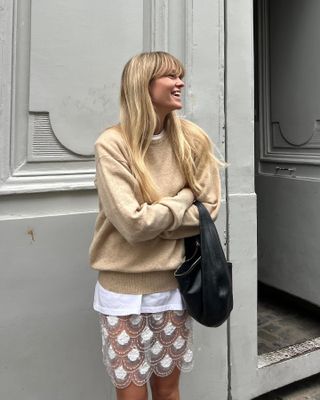 Jeannette Madsen wearing a camel sweater and sheer skirt