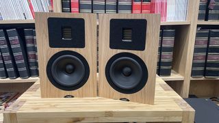 Neat Petite Classic speakers in oak finish on a wooden rack