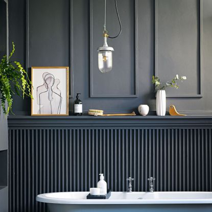 Dark painted bathroom with panel moulding feature wall, blue bathtub