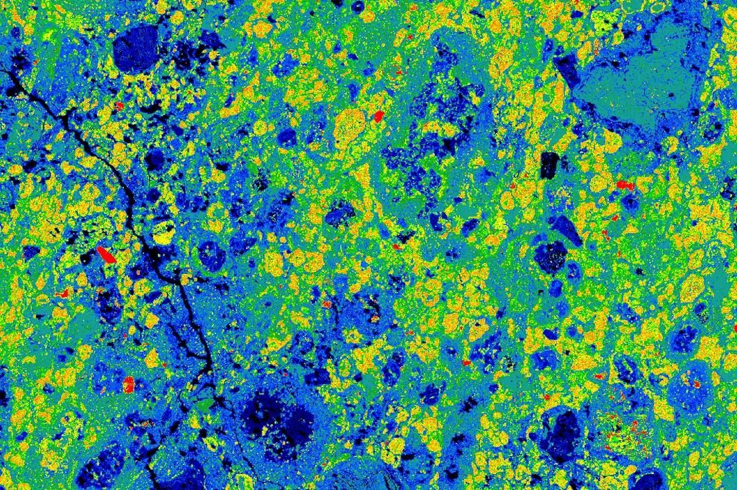 A slice of the Aguas Zarcas meteorite shows different minerals in different colors; for example, tochilinite in yellow and olivine in dark blue.