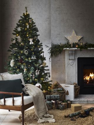 Christmas tree with natural wooden and paper decorations, garland on mantle, open fire, armchair, presents