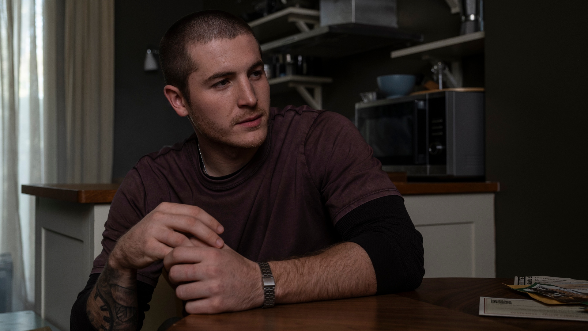 Liam sits at a table in Code of Silence