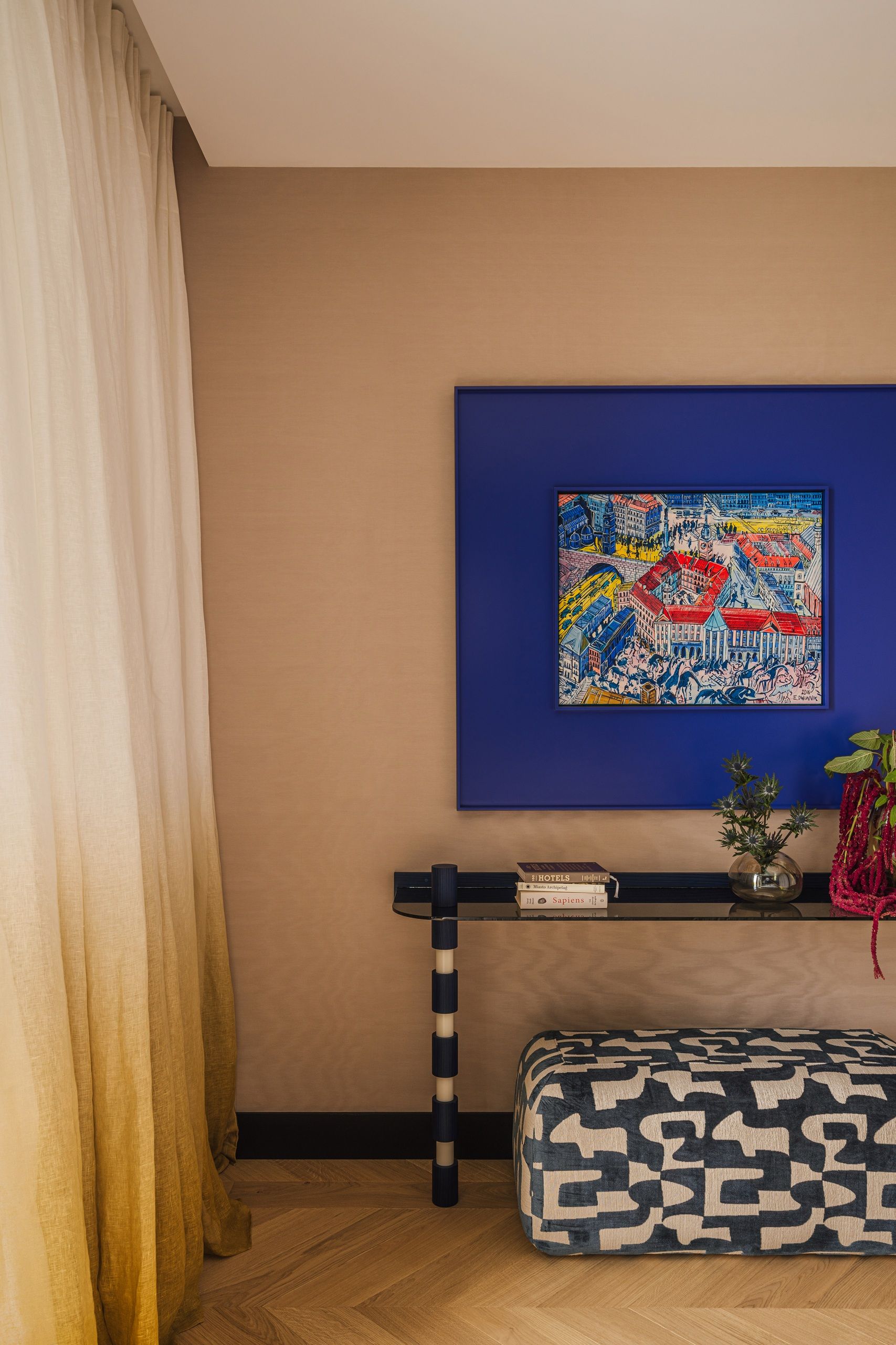 a room with an artwork with a bright blue surround and a console table
