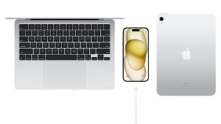 The iPhone 15 with a USB-C cable next to a MacBook and iPad