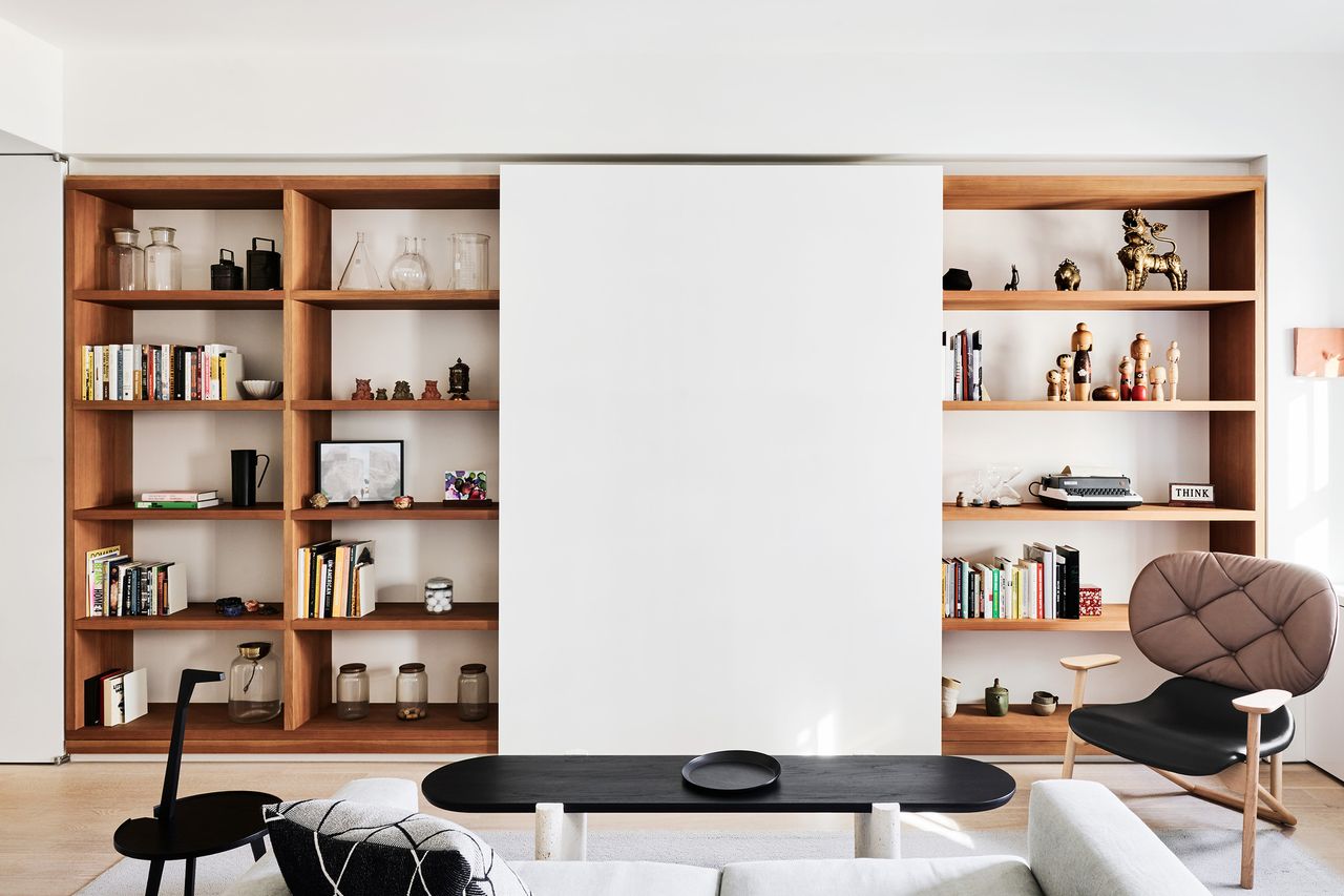 sliding TV cover in display shelves with armchair, sofa, and coffee table