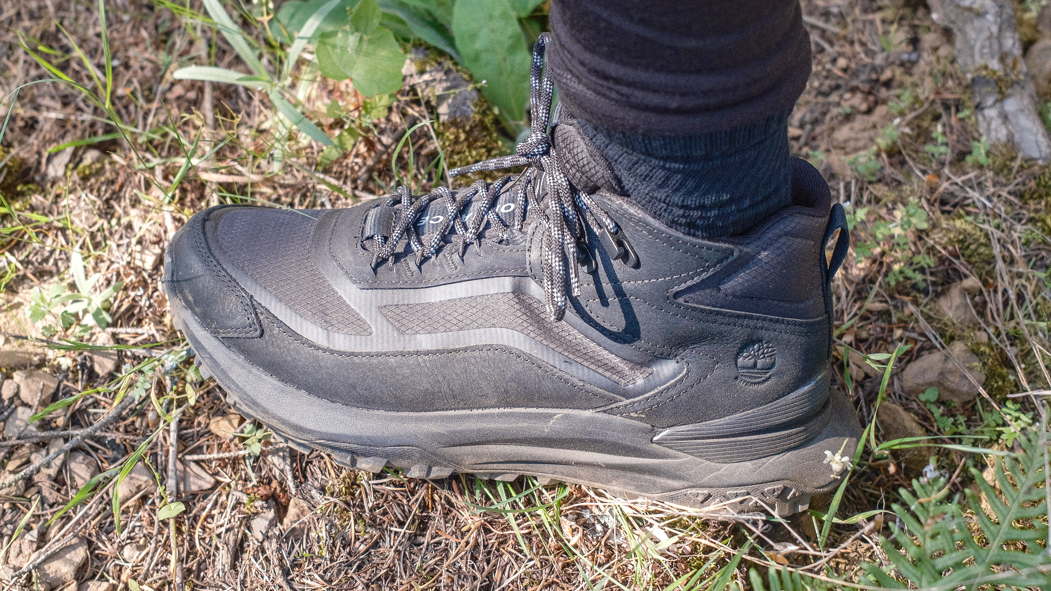 Close-up of the side of the Timberland Motion Access Mid Waterproof Sneakers (shown in black) on a hiker's feet