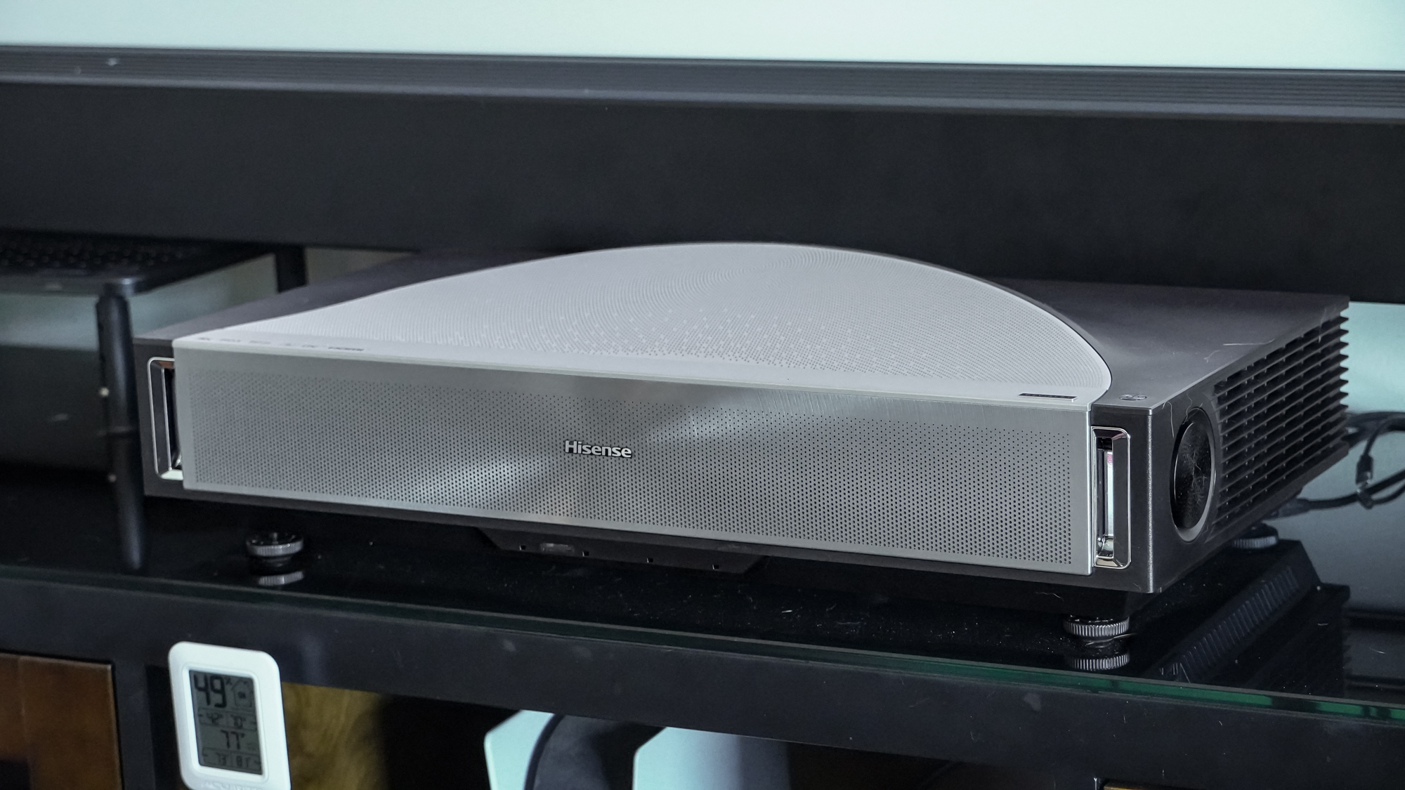 A Hisense PX4 Pro projector on a home media center shelf