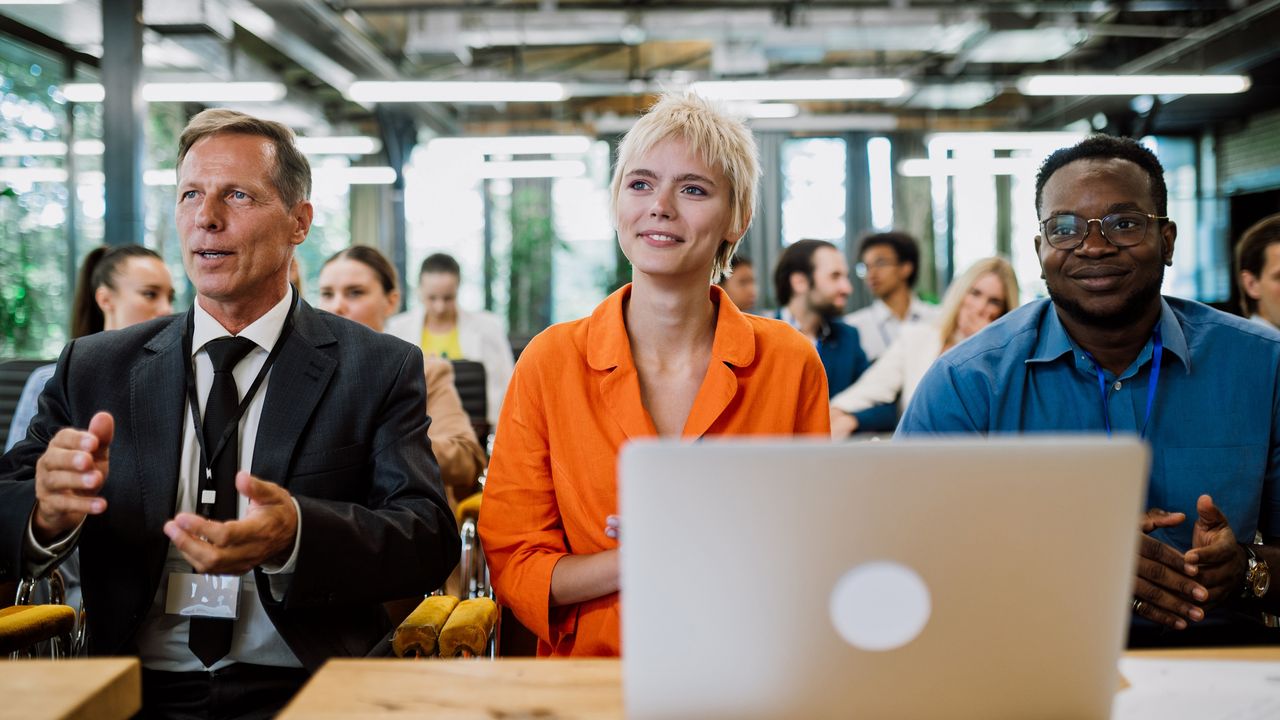 Three adults look attentive during an office meeting.