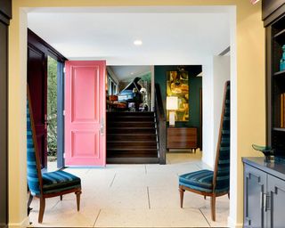 hallway with stairs white walls and pink door