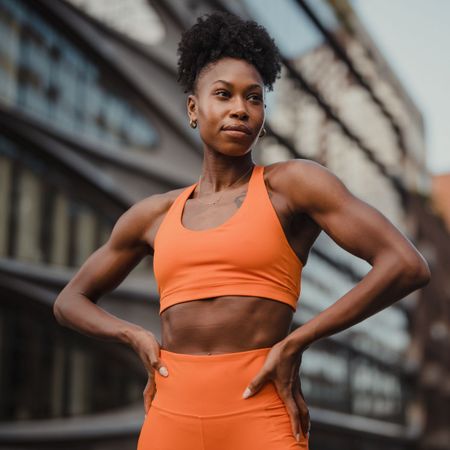 A woman stood with her hands on her hips in matching orange gymwear