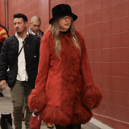  Taylor Swift looks on prior to a game between the Kansas City Chiefs and the Houston Texans at GEHA Field at Arrowhead Stadium on December 21, 2024 in Kansas City, Missouri. She wore a red penny lane coat and a new toi et moi diamond ring