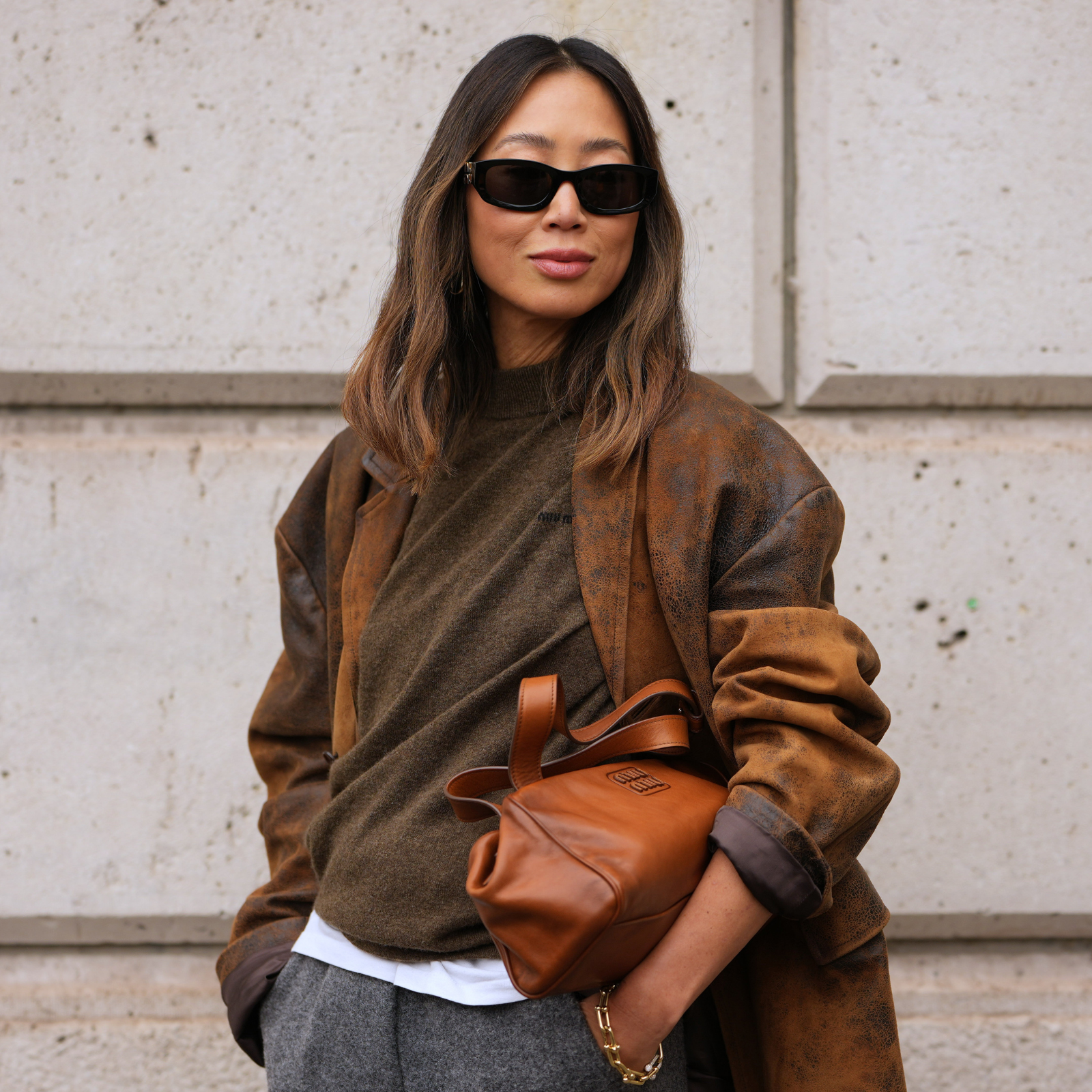 A woman wearing a brown cashmere sweater and sunglasses. 